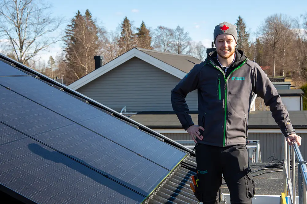 Gustav står uppe på ett tak där solceller monteras
